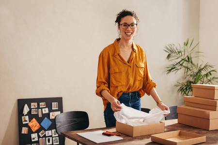 Woman packing parcel boxes for customers at home office