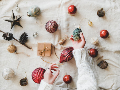 Christmas decoration toys and womans hands with pine cone