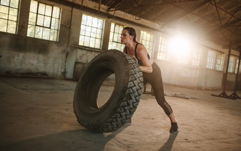 Fit woman doing tire flipping workout