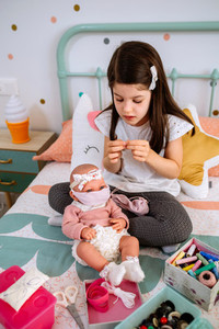 Girl sewing face masks for herself and her baby doll
