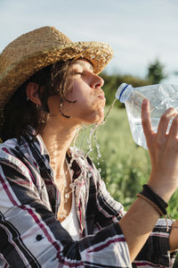 Farmer woman with mouthful of water in a crop field