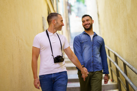 Gay couple tourists walking hand in hand on the street