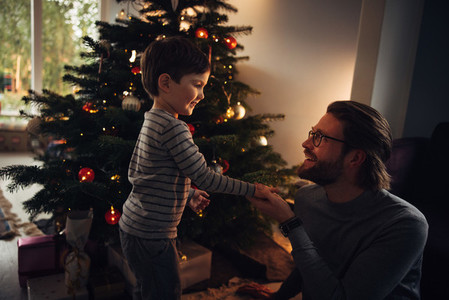 Father and son by a Christmas tree at home