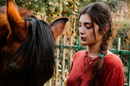 A woman caressing and talking to his horse in the countryside