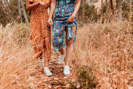 Two young lesbians walking in the woods wearing long dresses