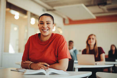 Portrait of a smiling girl sitting in university classroom