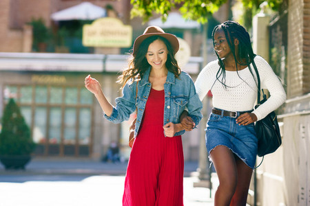 Two female walking together on the street  Multiethnic friends