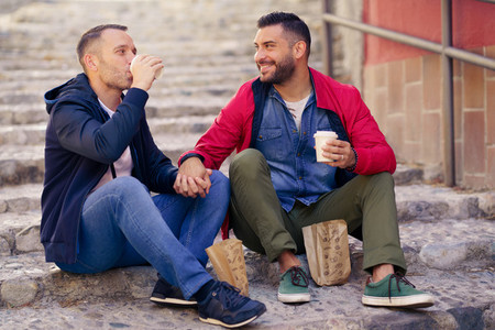 Gay couple having a take away meal on the street