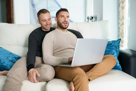 Gay couple consulting their travel plans together with a laptop