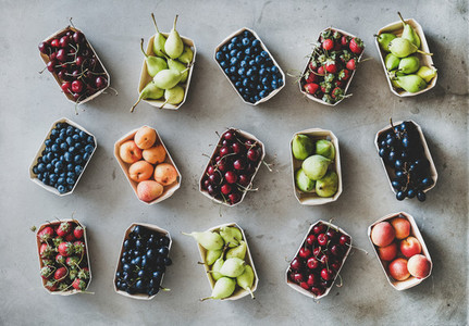 Flat lay of various fruits and berries over grey concrete background