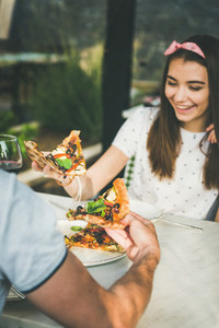 Young caucasian couple eating pizza and drinking wine in restaurant
