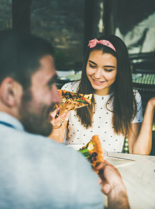 Young happy caucasian couple eating pizza in cafe