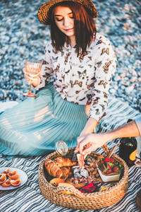 Couple having picnic at seaside with sparklng wine and appetizers