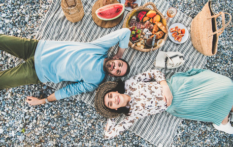 Young couple lying on blanket  smiling and looking above