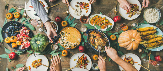 Friends feasting at Thanksgiving Day table with turkey  wide composition