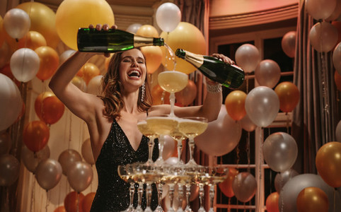 Excited woman filling up champagne pyramid at party