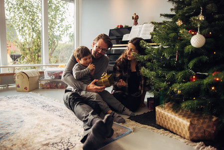 Parents giving Christmas gifts to their son