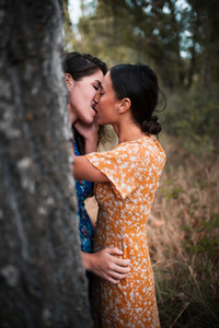 Two young lesbians kissing and caressing each other in the woods
