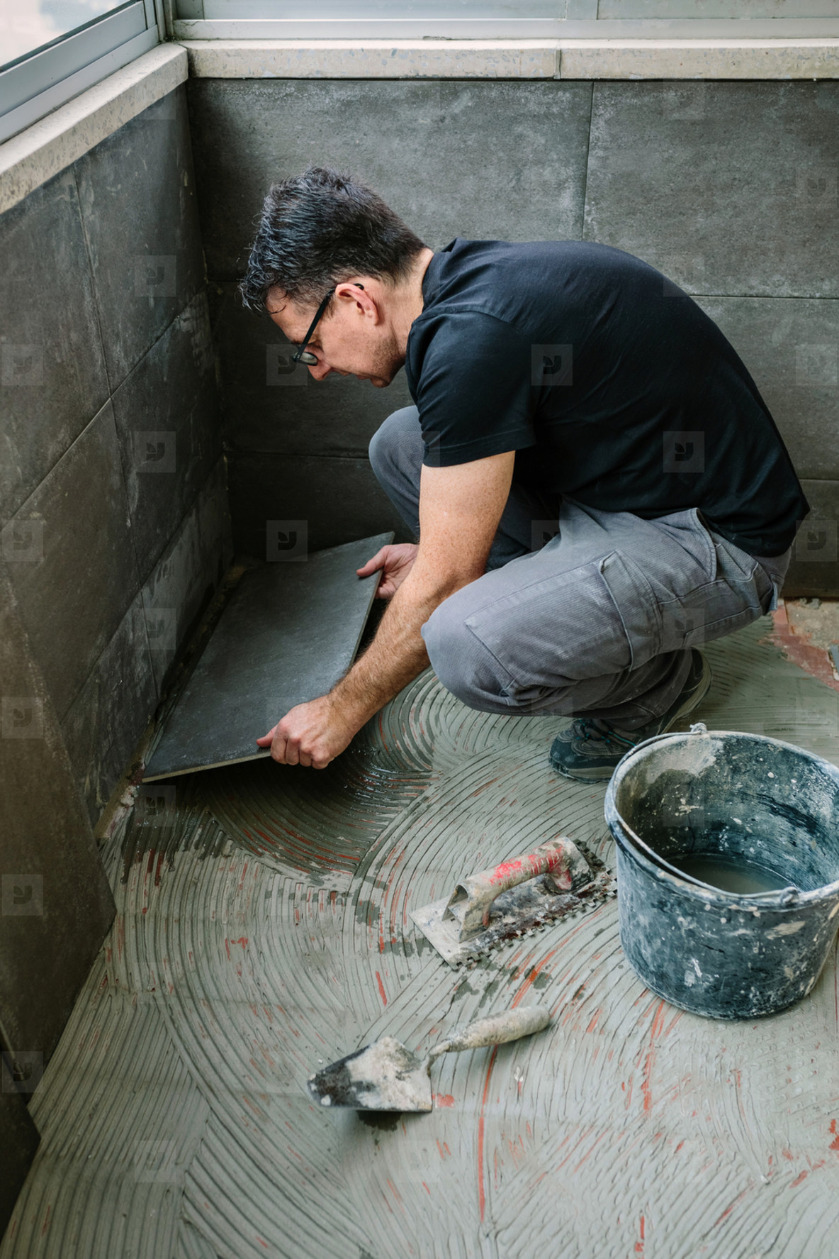 Workman laying tiles on a terrace
