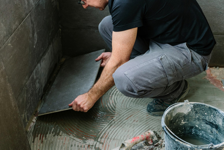 Workman laying tiles on a terrace
