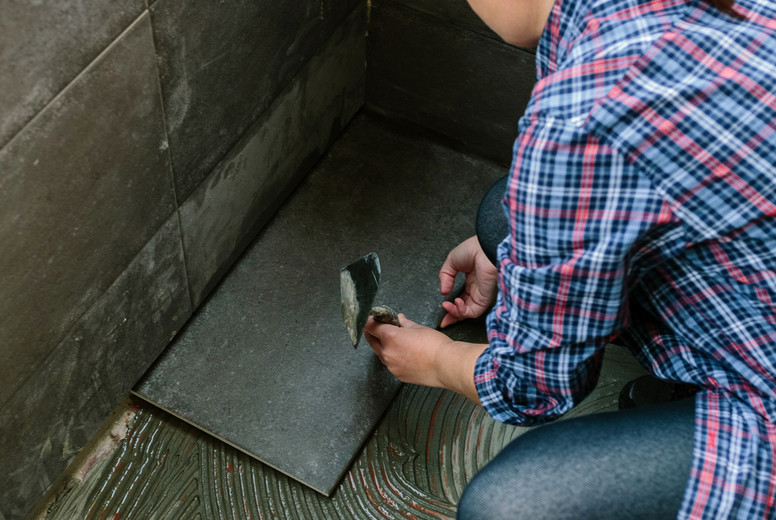 Female manual worker laying a new tile floor