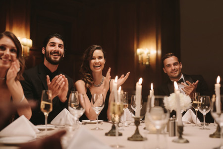 High society people clapping hands at dinner party