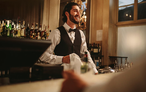 Smiling barman standing behind the counter
