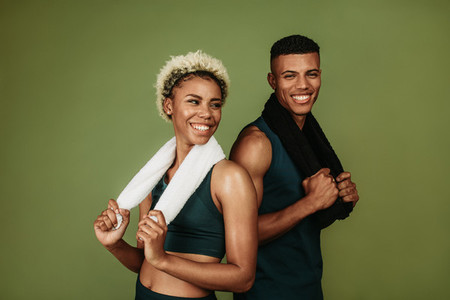 Happy athletic couple standing together holding towels