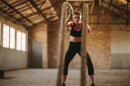 Strong woman working out with battle rope