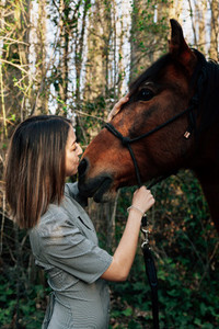 A woman caressing and talking to his horse in the countryside