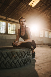 Woman sitting by a big tire after workout