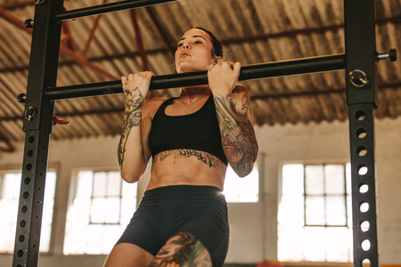 Woman doing pull up workout in empty factory shade