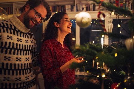 Couple having fun decorating Christmas tree