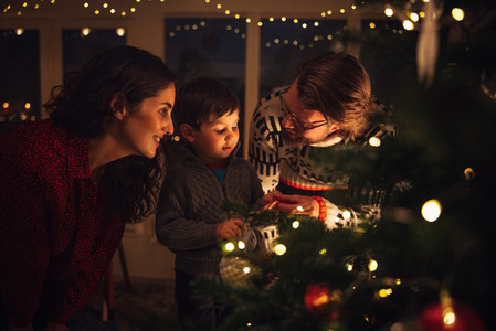 Boy decorating Christmas tree with parents