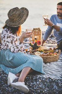 Young couple having picnic with sparkling wine and tasty appetizers