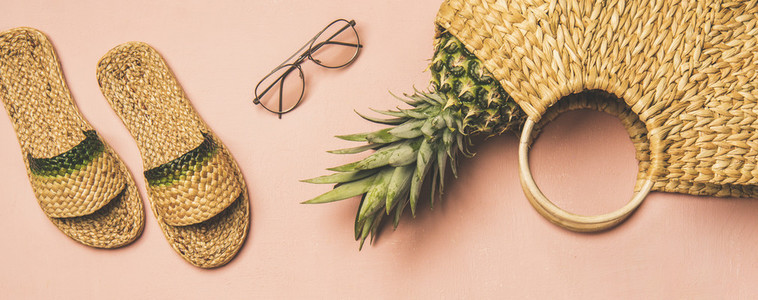 Summer apparel items and pinapple over pink background  wide composition