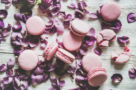 Sweet pink macaron cookies and lilac rose petals  top view