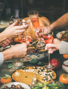 Friends clinking glasses at festive New Year table with snacks