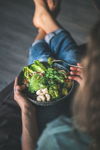Woman sitting at home and eating vegan superbowl