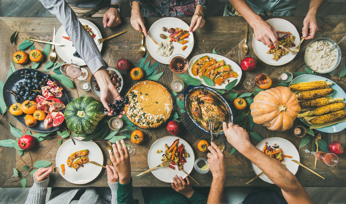Friends feasting at Thanksgiving Day table with turkey top view
