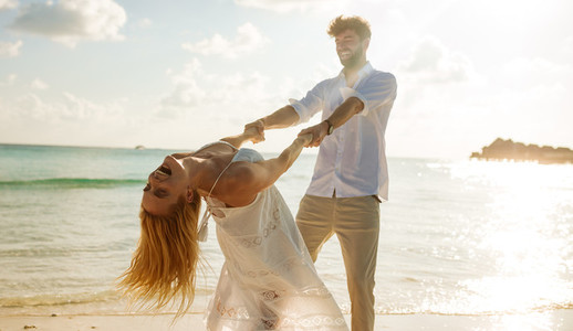 Couple on a honeymoon spinning around on the beach
