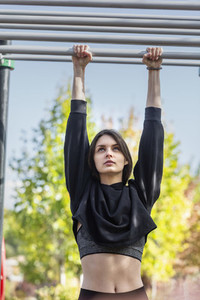 Fit young woman hanging from monkey bars at playground