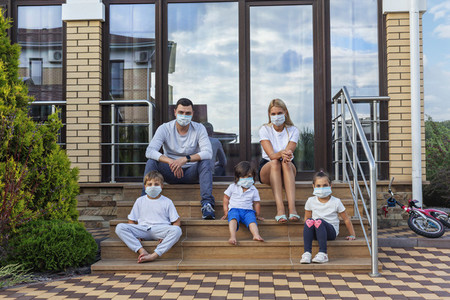 Portrait family in face masks on patio steps of house