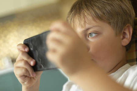 Close up focused boy playing video game on smart phone