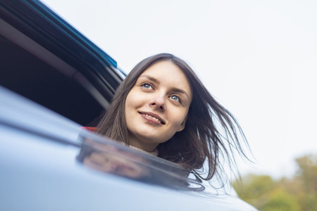 Portrait happy with carefree young woman leaning out car window