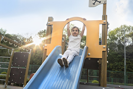 Portrait carefree girl on sunny playground slide
