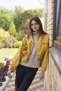 Portrait beautiful young woman in yellow jacket outside house