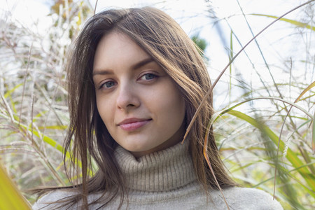Close up portrait beautiful young brunette woman in tall grass