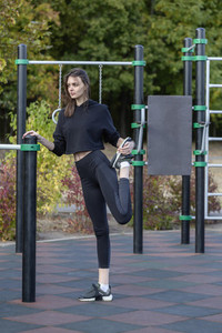 Fit young woman stretching leg at park playground