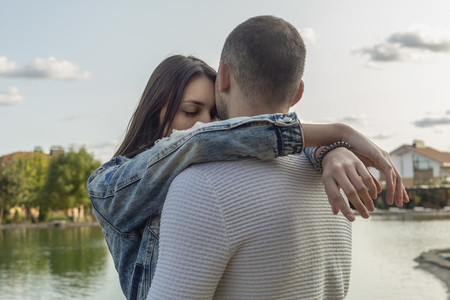 Serene with affectionate young couple hugging at lakeside